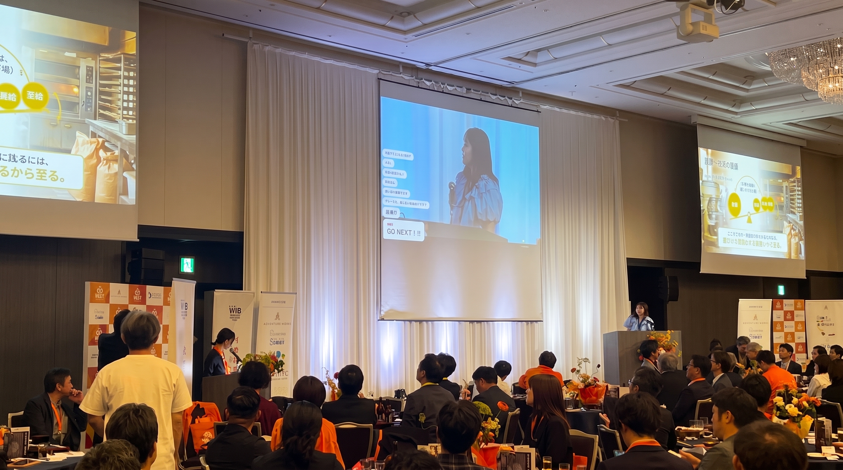会場スクリーンに映る登壇者と聴衆